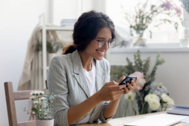 Mutlu genç kadın gülümsemesi cep telefonundan iyi bir mesaj alır.