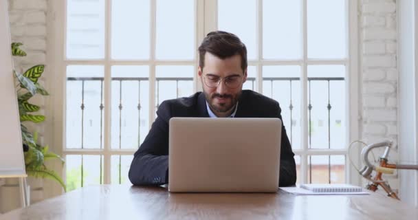 Uomo d'affari sorridente che lavora su laptop utilizzando il software aziendale in ufficio — Video Stock