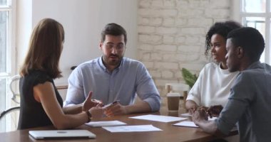 Takım çalışması yapan çeşitli iş adamları konferans masasında otururlar.