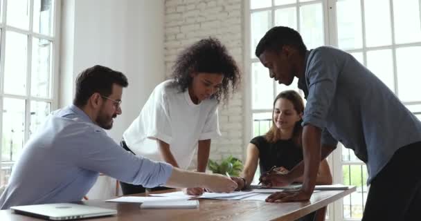 Grupo de colegas africanos y caucásicos analizan papeleo en reunión de equipo — Vídeos de Stock