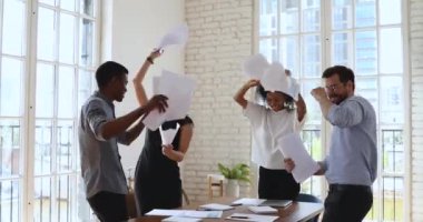 Mutlu çok ırklı iş adamları dans ediyor. Evrakları ofise atıyorlar.