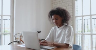 Gülümseyen Afrikalı iş kadını iş yerinde dizüstü bilgisayar kullanıyor.