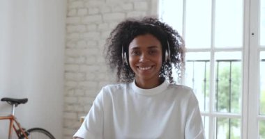 Mutlu Afrikalı iş kadını kablosuz kulaklık takıyor ve video görüşmesi yapıyor.