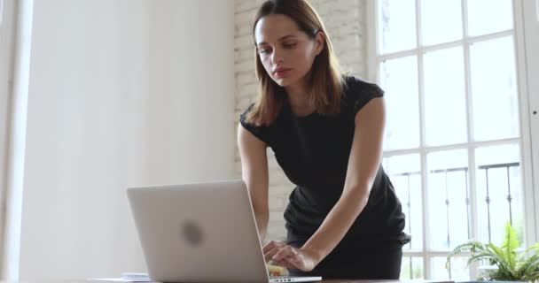 Орієнтована молода бізнес-леді, використовуючи ноутбук роблячи нотатки на робочому місці — стокове відео