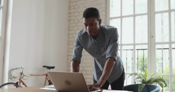 アフリカ系アメリカ人のビジネスマンがオフィスのデスクでノートパソコンを使って — ストック動画