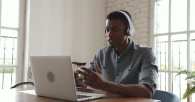 Genç Afrikalı iş adamı kulaklık takıyor ve laptoptan arıyor.