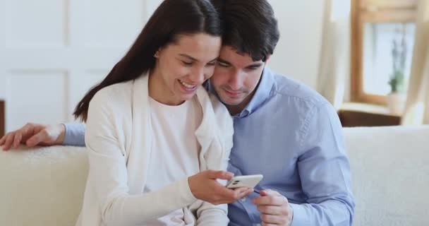 Pareja feliz viendo videos divertidos en las redes sociales en el teléfono inteligente . — Vídeo de stock