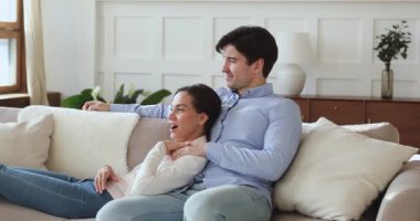 Kocasıyla kanepede oturup film tartışan mutlu, genç bir kadın..