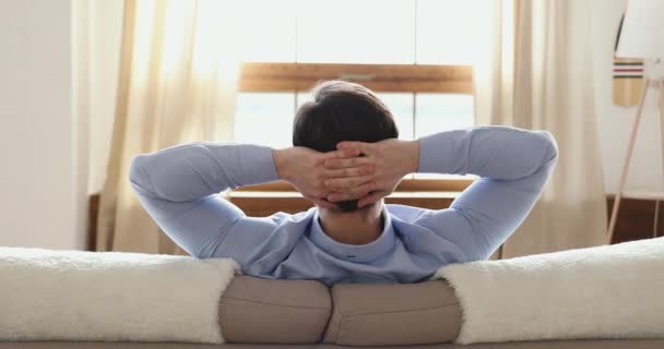 Consciente chico joven apoyado en cómodo sofá solo en casa . — Vídeo de stock