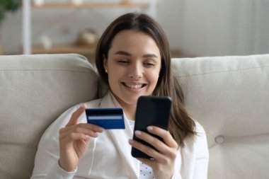 İnternet üzerinden kredi kartı ve akıllı telefon kullanan bir kadın.
