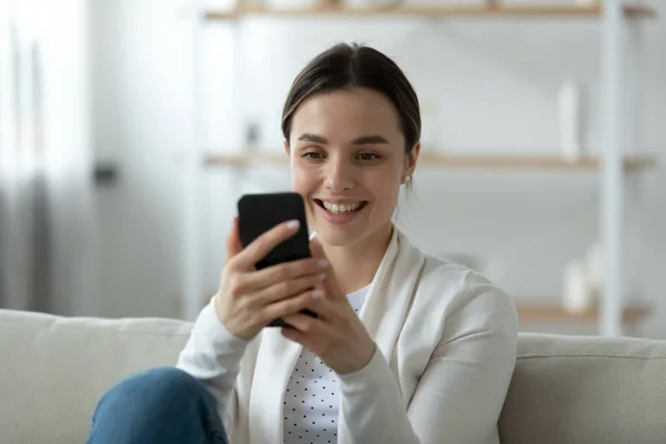 Smiling woman holding mobile phone dialing number, makes videocall — Stock Photo, Image