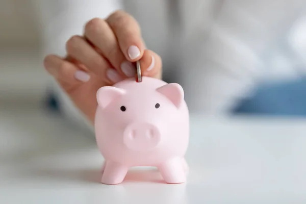 Closeup image female fingers puts coin inside of piggy bank — Stock Photo, Image