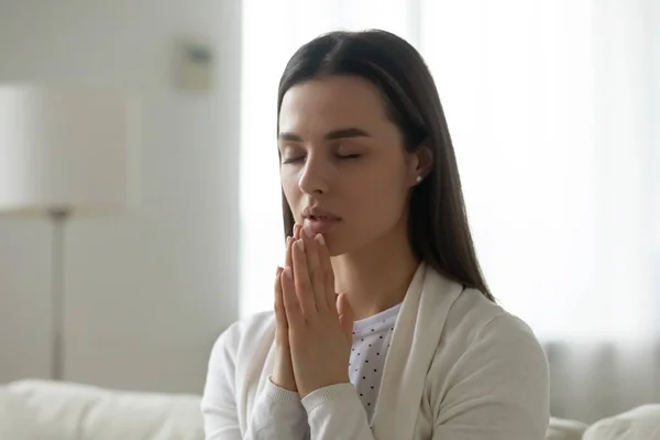 Calm candid young woman joined hands and pray at home — Stock Photo, Image