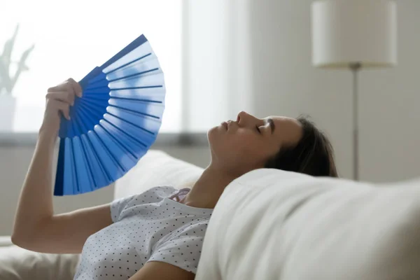 Woman feels sluggish due unbearable heat waves fan cooling herself