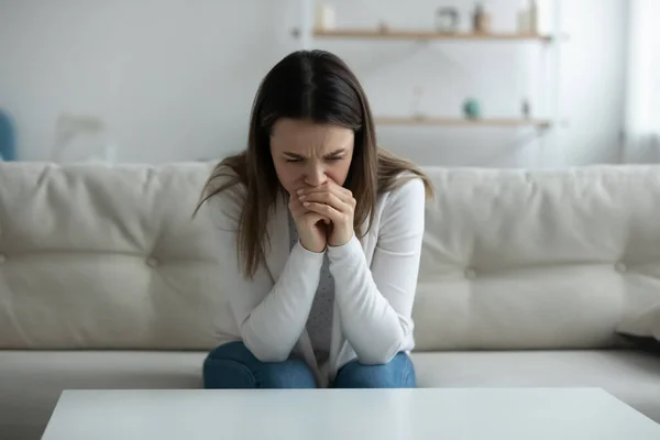 Mujer joven deprimida llorando sentada en el sofá sola en casa — Foto de Stock