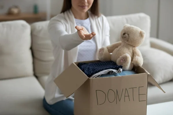 Woman with arm stretched sit near donation box with clothes — Stock Photo, Image