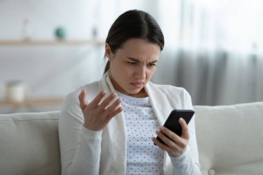Alet ile ilgili sorunları olan, akıllı telefonu tutan sinirli bir kadın rahatsız olur.