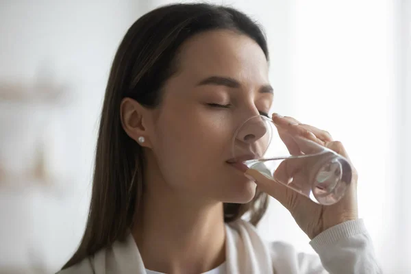 Mulher milenar segurando vidro bebendo água ainda natural — Fotografia de Stock