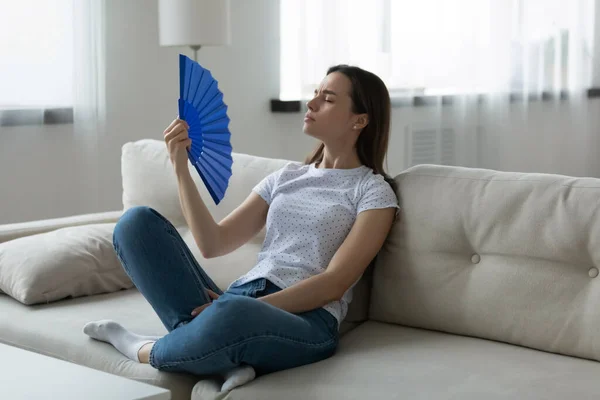 Woman suffers from unbearable hot weather waving fan cooling herself — Stock Photo, Image