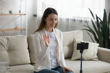 Kadın akıllı telefonu tripoda koyup çevrimiçi canlı yayın yapıyor.