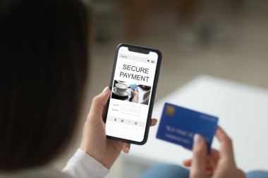 Akıllı telefon ve kredi kartı tutan kadın ödemeyi internetten yapıyor