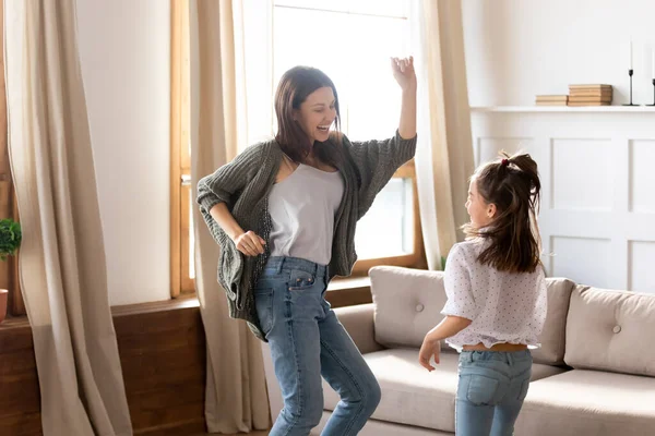 Feliz madre emocionada e hija bailando en la sala de estar moderna —  Fotos de Stock