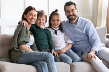 Mutlu anne ve baba portresi ve koltukta oturan çocuklar.