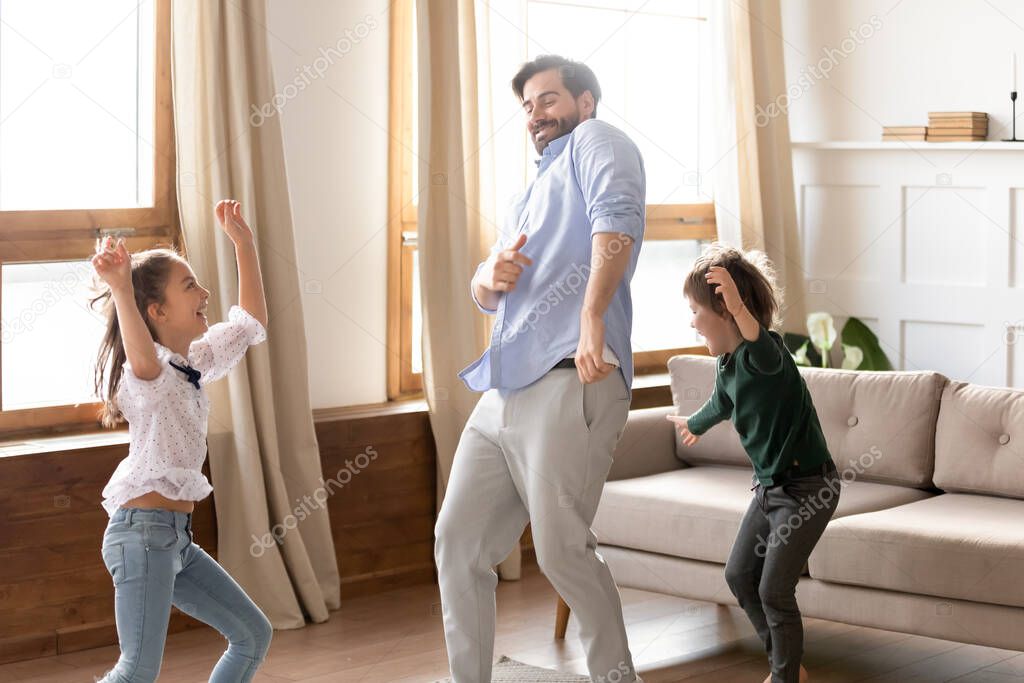 Happy father with son and daughter dancing in living room