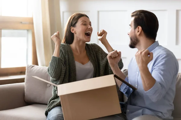 Spännande överlycklig man och kvinna packa upp efterlängtade paket tillsammans — Stockfoto