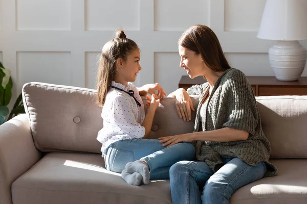 Zorgzame moeder en kleine dochter chatten, zitten op gezellige bank — Stockfoto