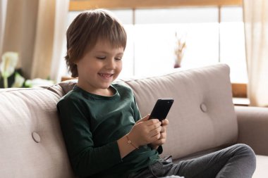 Akıllı telefon kullanan sevimli küçük çocuk, cep telefonuyla eğleniyor.