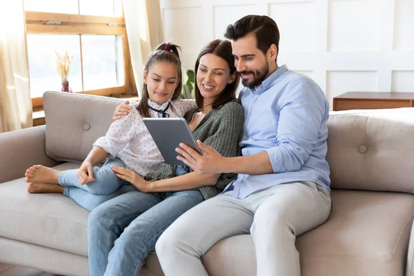Sevimli kızı olan mutlu ebeveynler birlikte bilgisayar tableti kullanıyorlar. — Stok fotoğraf