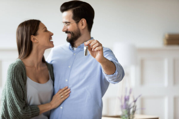 Close up happy husband hugging wife and showing keys