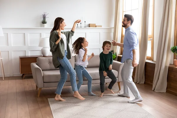 Padres felices con niños bailando juntos en la moderna sala de estar —  Fotos de Stock