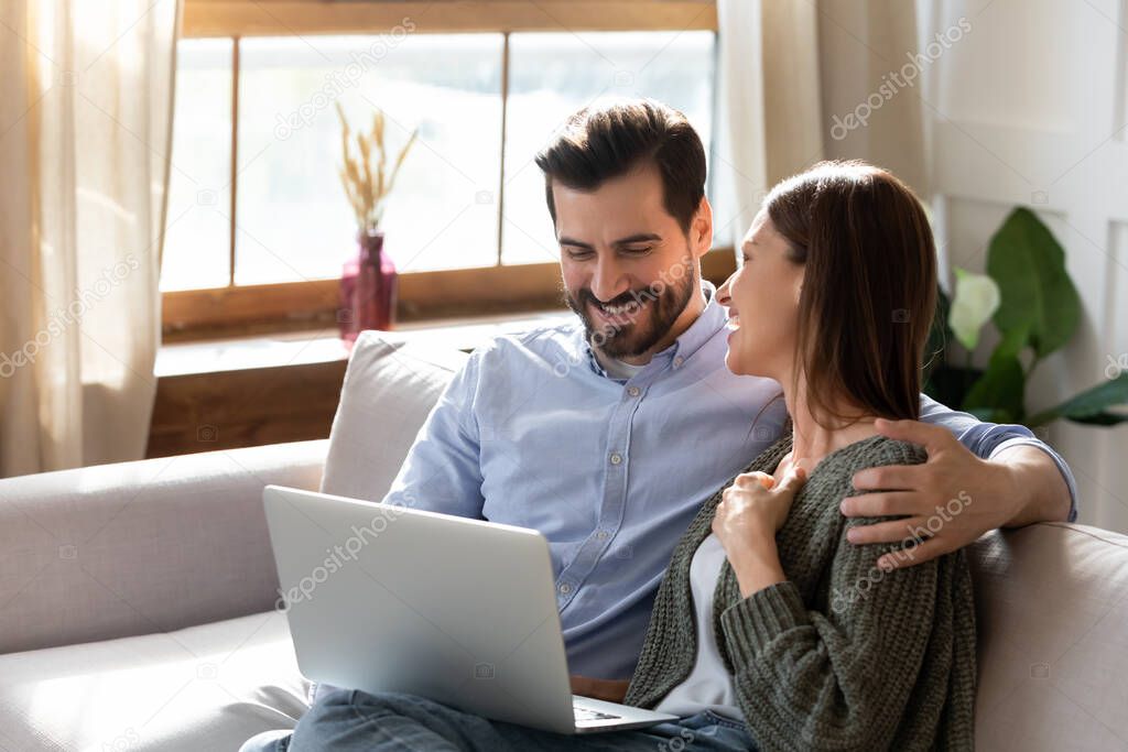 Happy man and woman hugging, having fun with laptop together