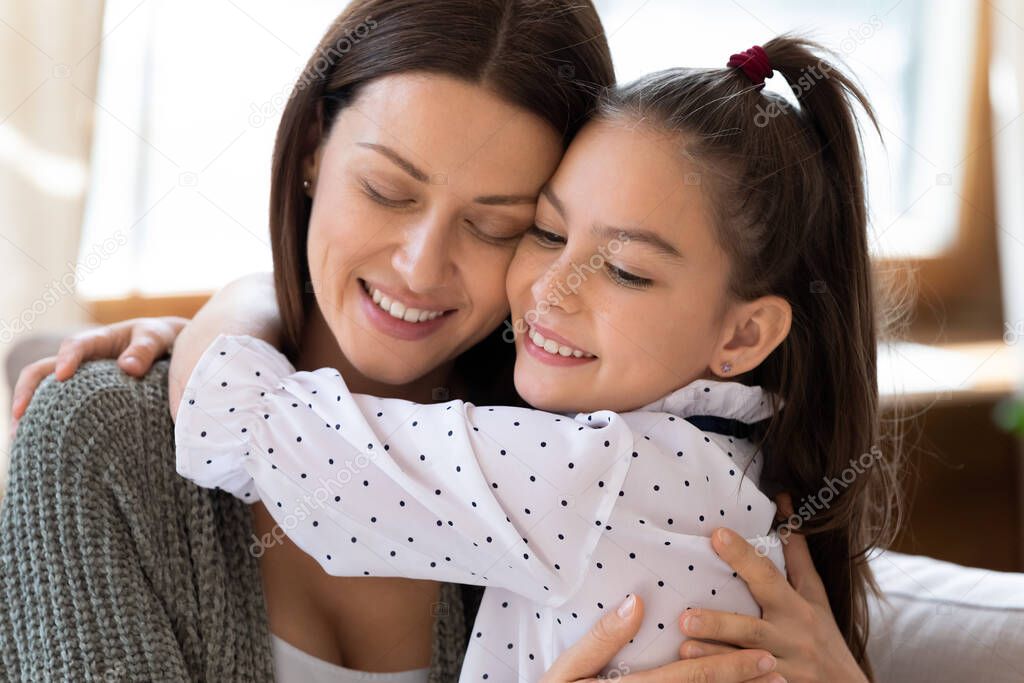 Close up smiling mother and adorable daughter hugging