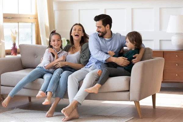 Heyecanlı anne ve baba kanepede çocuklarla eğleniyor.