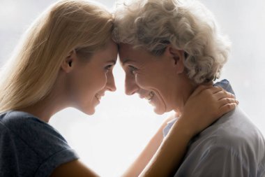 Yetişkin bir kızın yaşlı bir anneyle alınlarına dokunmasıyla karşı karşıyayız.