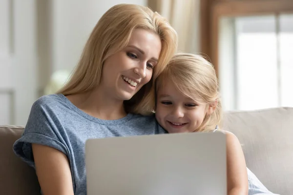 Mutter sitzt auf Couch mit Tochter und hat Spaß mit Laptop — Stockfoto