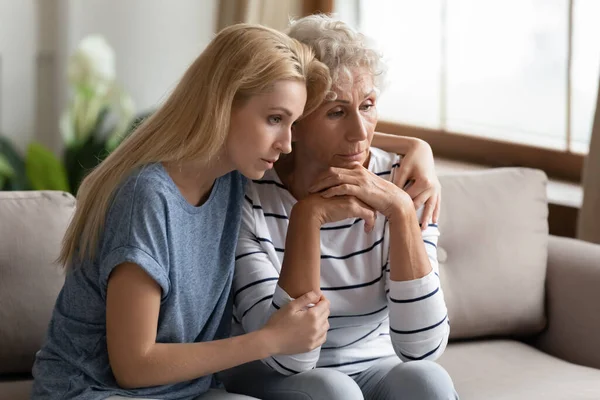 Grownup adult daughter soothes elderly mother shares her mental pain