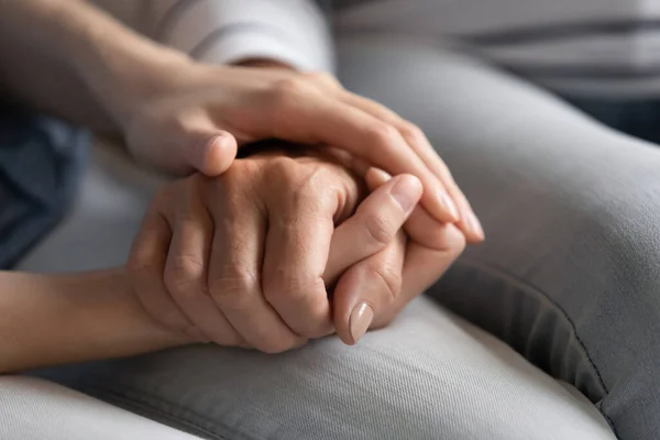 Millennial daughter holds hand of elderly mother express care closeup — Stock Photo, Image