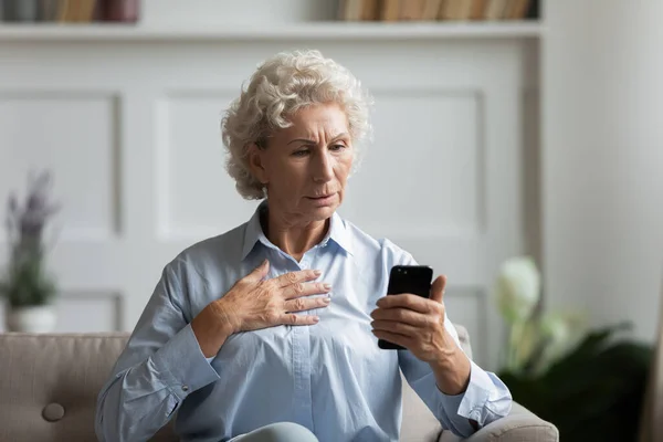 Frustrated mature woman looks at smartphone screen read bad sms — Stock Photo, Image