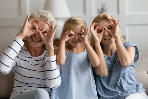 Три покоління жінок з пальцями роблять біноклі, як окуляри — стокове фото