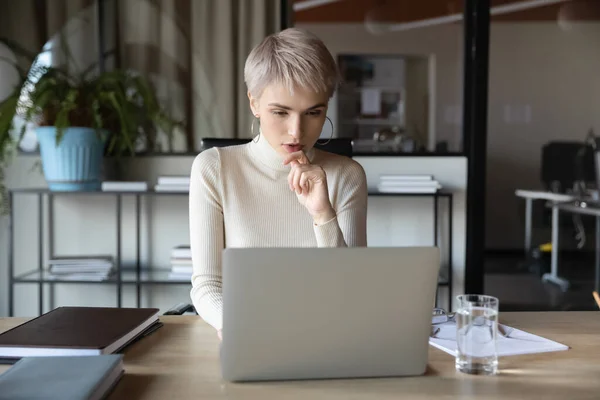 Geconcentreerde zakenvrouw die werkt met behulp van een laptop aan haar bureau — Stockfoto