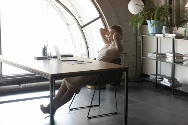 Affärskvinna vilar lutad på kontorsstol beundrar utsikten från fönstret — Stockfoto