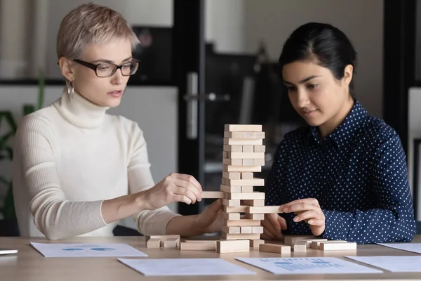 İki iş kadını ahşap bloklardan kule inşa edip oyun oynuyorlar. — Stok fotoğraf