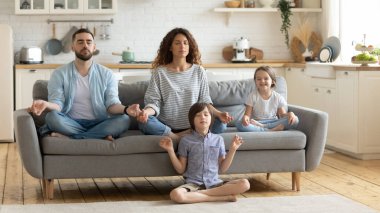 Rahat genç bir aile, tatlı çocuklar oturuyor ve meditasyon yapıyor..