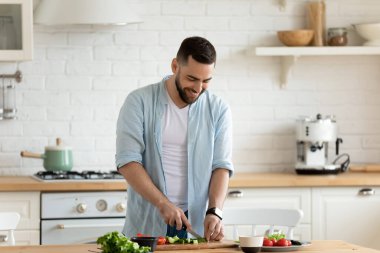 Salata yapmak için sebze doğrayan mutlu sakallı adam..
