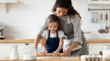 Gülümseyen anne küçük kızına para dağıtmayı öğretiyor.