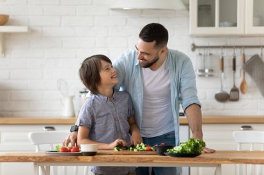 Baba oğluna bıçak kullanmayı öğretiyor. Birbirlerine bakıyorlar..